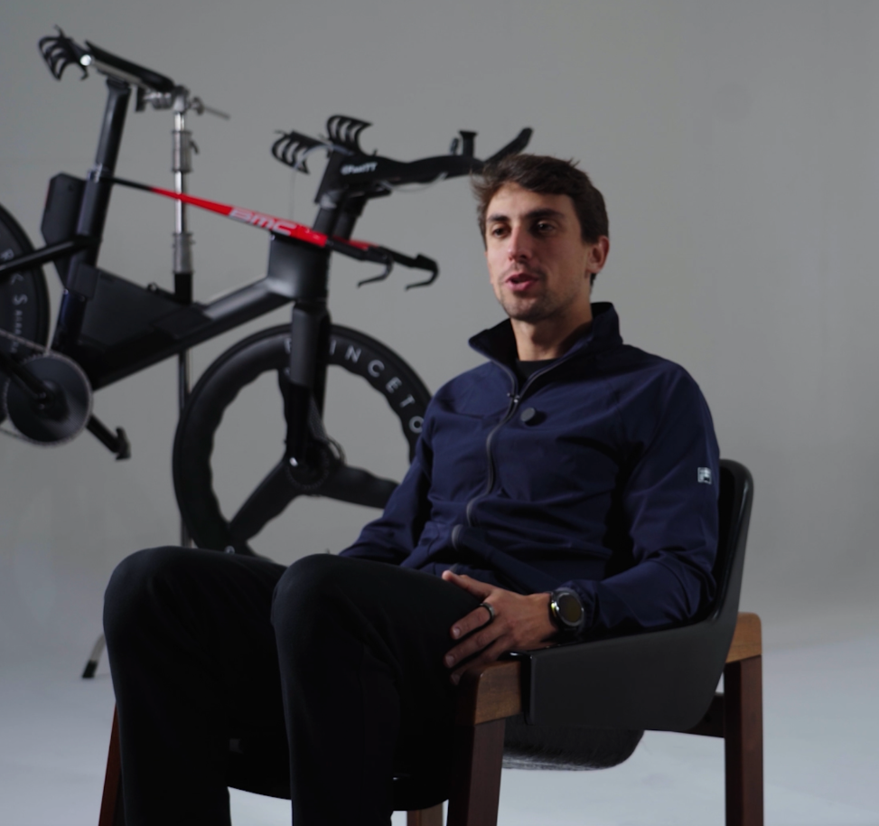 Fellipe Santos, triatleta e mentor da MAP, sentado ao lado de sua bicicleta de triathlon