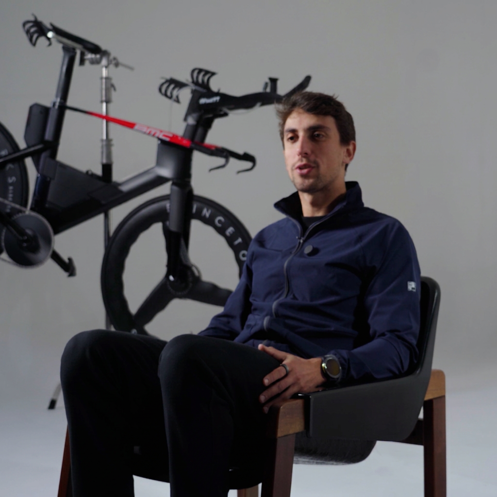 Fellipe Santos, triatleta e mentor da MAP, sentado ao lado de sua bicicleta de triathlon